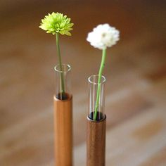 two small vases with flowers in them on a wooden table next to each other