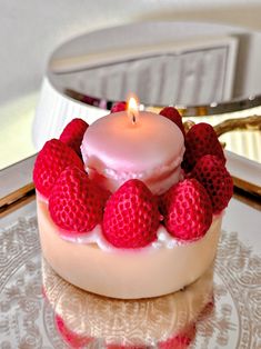 a small cake with strawberries on top and a lit candle in the middle sitting on a plate