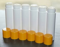 several tubes lined up on a table with orange caps next to each other and one tube in the middle