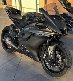 a black motorcycle parked in front of a building next to another bike on the ground