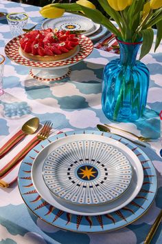 a table topped with plates and bowls filled with fruit on top of a blue table cloth