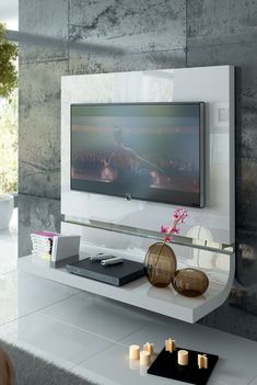 a flat screen tv mounted to the side of a wall next to a vase with flowers