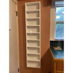 an empty white book shelf in the corner of a kitchen