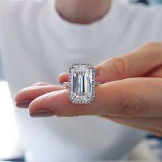 a woman holding an emerald cut diamond ring