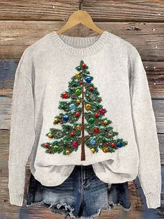 a white sweater with a christmas tree on the front, and blue jean shorts underneath