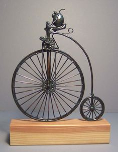 a metal figurine on a wooden stand with wheels and a cat sitting on top