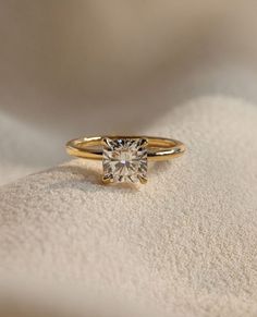 a yellow gold engagement ring with a single diamond on the top, sitting on a white cloth