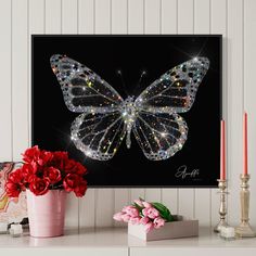 a butterfly with sparkles on its wings sitting next to a pink vase filled with flowers