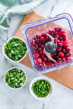 cranberry sauce in a food processor surrounded by bowls of green onions and spinach