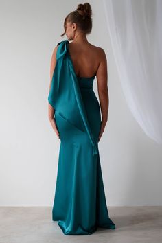 the back of a woman in a teal gown with one shoulder draped over her shoulders