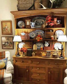 a wooden hutch filled with plates and vases on top of it's shelves