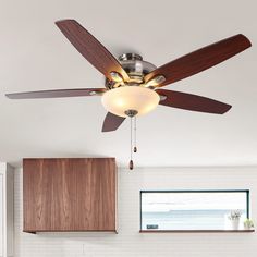 a ceiling fan in a kitchen with wooden cabinets