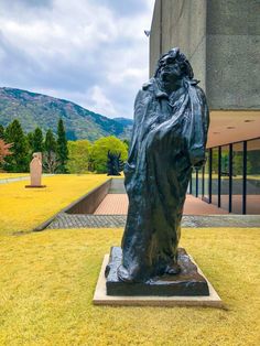 a statue in front of a building with mountains in the backgrouds behind it