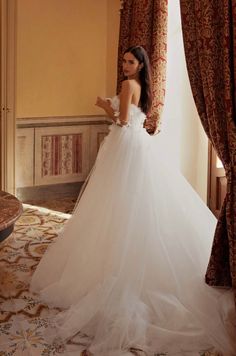 a woman in a wedding dress looking out the window