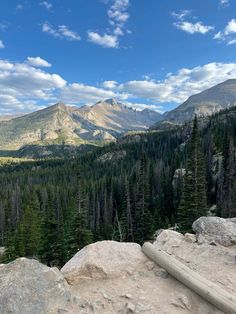 the mountains are full of trees and rocks with some clouds in the sky above them