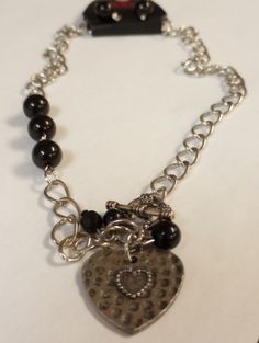 This is a fun brand new with tags set that would make a great gift. The necklace has larger links with a few black beads and a hammered silver tone metal heart pendant. It has a toggle clasp and measures 20" long. The pierced hook earrings have black beads that match the necklace. Metal Double Heart Necklace With Heart Beads, Double Heart Metal Necklace With Heart Beads, Heart Shaped Metal Jewelry With Beaded Chain, Heart-shaped Metal Beaded Chain Jewelry, Valentine's Day Beaded Metal Jewelry, Vintage Jewelry With Heart Beads And Dangle Shape, Vintage Dangle Heart Beads Jewelry, Vintage Dangle Jewelry With Heart Beads, Heart-shaped Beaded Chain Jewelry For Valentine's Day