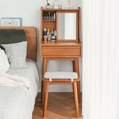 a bedroom with a bed, mirror and stool next to the bed in front of it