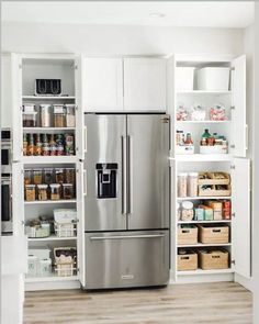 a stainless steel refrigerator and pantry in a white kitchen with open shelve doors