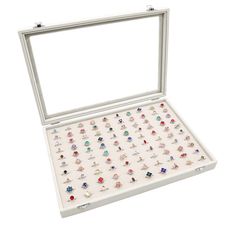 an open white box filled with lots of different colored rings and studs on top of each other