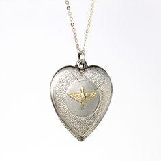 Historical vintage circa 1940s sterling silver Prop and Wings heart pendant! This classic pendant has a heart shape, and features the Prop and Wings Military emblem on the front, and is shown modeled on a brand new sterling silver 18" chain. A wonderful piece of vintage aviation sweetheart jewelry!  ERA - Circa 1940s - Retro METAL / MATERIAL - Sterling silver pendant, sterling silver chain MARKINGS / HISTORY - Back of pendant is marked "sterling"  CONDITION - Good vintage condition. Sterling silver metal has been professionally polished & cleaned. Age appropriate patina & wear remains. Amazing vintage military pendant!  SIZE / MEASUREMENTS - Chain Modeled: 18 inches, Pendant (including bail): 1 1/4 x 7/8 inches, Weight (without chain): 3.52 grams PRESENTATION - Listing includes a complimen Puffy Heart Necklace, Sweetheart Jewelry, Vintage Aviation, Logo Gifts, Puffy Heart, Vintage Military, Locket Necklace, Metal Material, Heart Shape