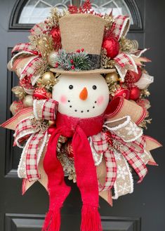 a christmas wreath with a snowman wearing a top hat and red scarf hanging from the front door