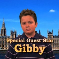 a young boy is standing in front of the big ben clock tower and has an ad for gibby on his shirt