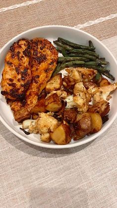 a white bowl filled with chicken, potatoes and green beans on top of a table