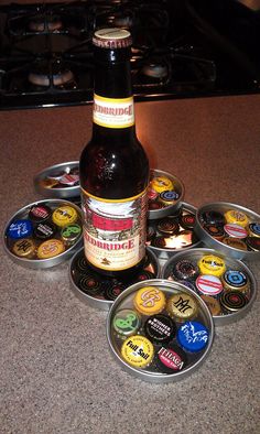 a bottle of beer sitting on top of a counter next to tins filled with buttons