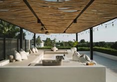 an outdoor living area with white couches and pillows