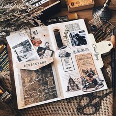 an open book sitting on top of a table next to some scissors and other items