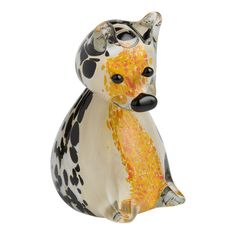 a glass animal figurine sitting on top of a white surface with yellow and black spots