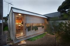 a house that is made out of metal and has plants growing on the outside wall