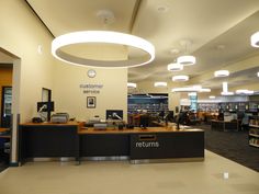 the interior of a public library with lights and bookshelves on either side of the counter