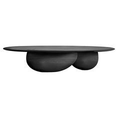 an oval table with two black plates on top and one round plate sitting on the other side