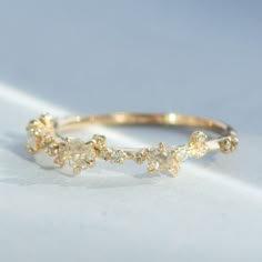 a close up of a gold ring on a white surface with small flowers in the middle