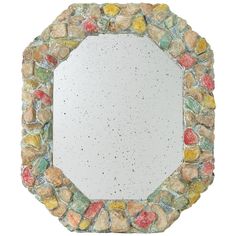 a mirror made out of rocks on a white background with lots of small stones around it