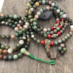 Beautiful Mix Jade Japa Mala from Nepal. You can choose between the mala that has unique mix metal beads and a main Nepali metal bead at the bottom of the mala necklace. Or the mix Jade mala that is all stone beads with no metal beads. A unique praying mala that can be used as a necklace or as an ornament. The mala has no clasp, you wear it over the head. The Mala with the metal beads and the red beads has a total length of 49cm- 19.25 inch long The mala that is all stone beads is 43cm- 17 inch Spiritual Colorful Beads Bracelet, Green Spiritual Beads For Healing, 8mm Oval Beads For Gifts, Green Spiritual Beads, 108 Count, Holistic Beaded Bracelets With Round Beads For Meditation, Green Mala With 8mm Beads For Healing, Multicolor Polished Beads Bracelet For Meditation, Multicolor Polished Beaded Bracelets For Meditation, Bohemian Multicolor 8mm Beads