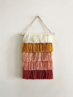 a multicolored wall hanging on a white wall with strings attached to the wall