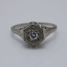 an antique style diamond ring with filigrees on the sides, set in white gold