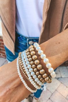 a close up of a person's arm wearing bracelets with pearls on them