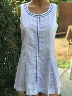 Here is a vintage 1970s white poly cotton tennis dress.Made by June Marks Tennis Fashions. Size 10.Following  are the measurements. Bust 34" waist 32",Hips full with pleats,Length 30".Zips up the back.Small square print on the solid white fabric.Pleats on front and Le back.Blue trim.In nice vintage condition.Please take special consideration of measurements. 1970s sizing was very small to today's standards. Tennis dresses were very short not like a regular dress. So please take special note of length. If you live overseas please email me first before purchasing for mailing cost. Price quoted is for USA only White Summer Dress With Pintucks, Summer White Dress With Pintucks, Fitted Cotton Dress With Pintucks, Classic Fitted Tennis Dress For Spring, Classic Fitted Summer Tennis Dress, Classic Fitted Tennis Dress For Summer, Fitted Cotton Tennis Dress For Spring, Classic Summer Tennis Dress, Classic White Tennis Dress For Spring