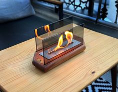 a wooden table topped with a glass case filled with fire and flames on top of it