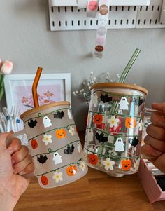 two people holding cups with halloween decorations on them