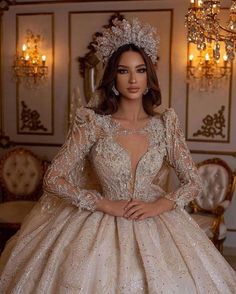 a woman in a wedding dress standing next to a chandelier with lights on it