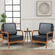 two black leather chairs sitting next to each other in front of a table with a potted plant on it