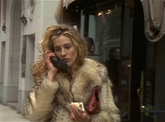 a woman talking on a cell phone while walking down the street with food in her hand