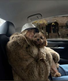 a woman sitting in the back seat of a car holding a dog