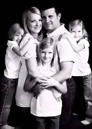 a black and white photo of a family posing for the camera with their arms around each other