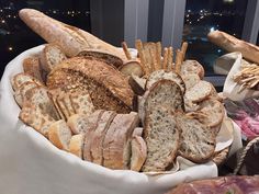 a basket filled with lots of different types of breads and pastries on top of a table