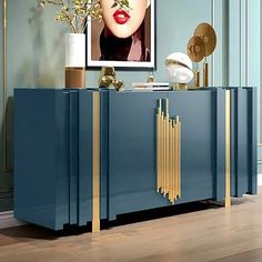 a red and gold sideboard in a blue room with a painting on the wall